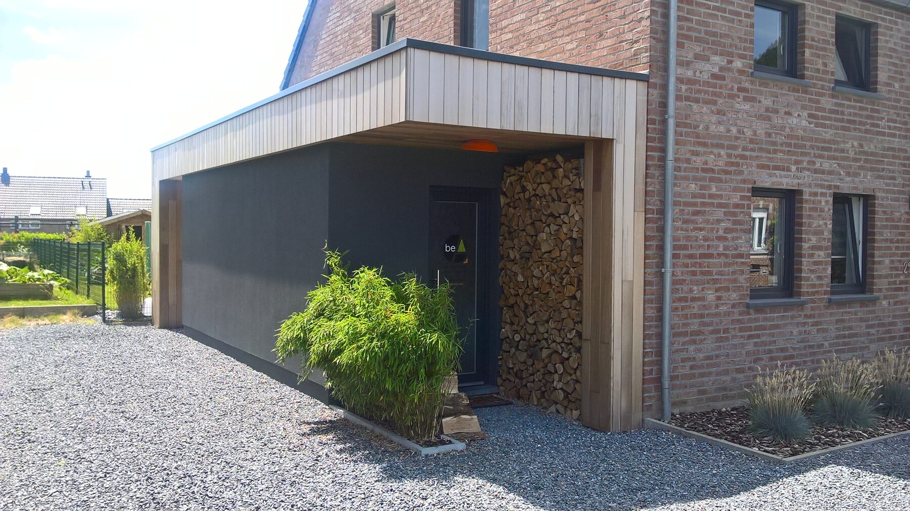 Extension contemporaine en bois créant une nouvelle entrée dans une habitation en brique